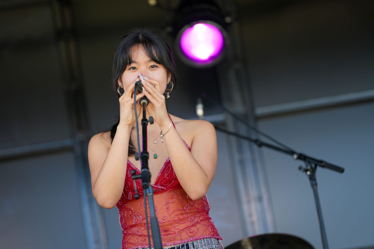 A girl singing into a microphone with a red strappy top on.